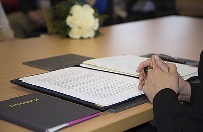 Person unterzeichnet offizielles Dokument mit Stift an einem Konferenztisch